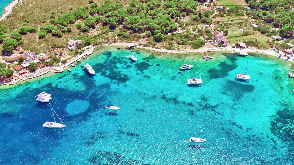Veduta aerea di una baia cristallina con barche a vela tra le isole della Dalmazia
