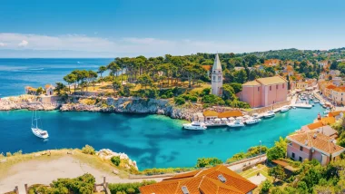 Vista panoramica di Lussino Veli Losinj, cittadina portuale istriana con chiesa storica e barche ormeggiate in acque azzurre