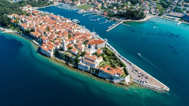 Rab Isole e vista aerea della cittadina istriana con tetti arancioni e una marina piena di barche, abbracciata da acque blu vivide.